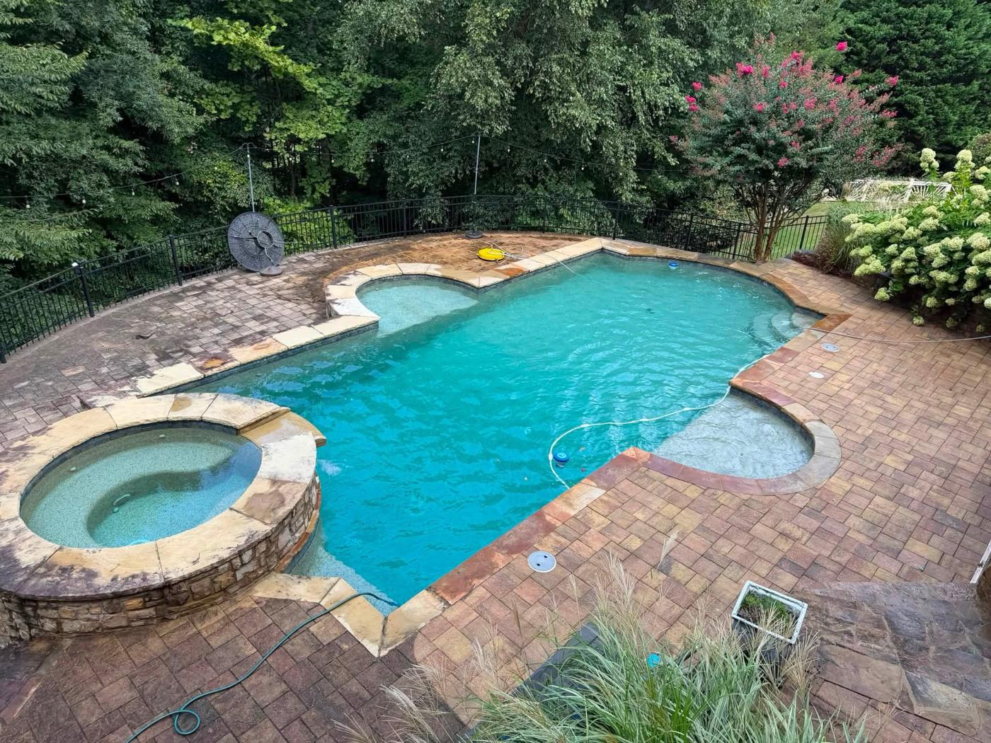 Pool deck mid-wash: dirty pavers on the left, clean pavers on the right